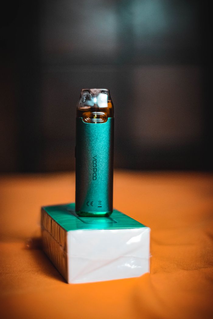 A stylish green vape device elegantly positioned on a matching box